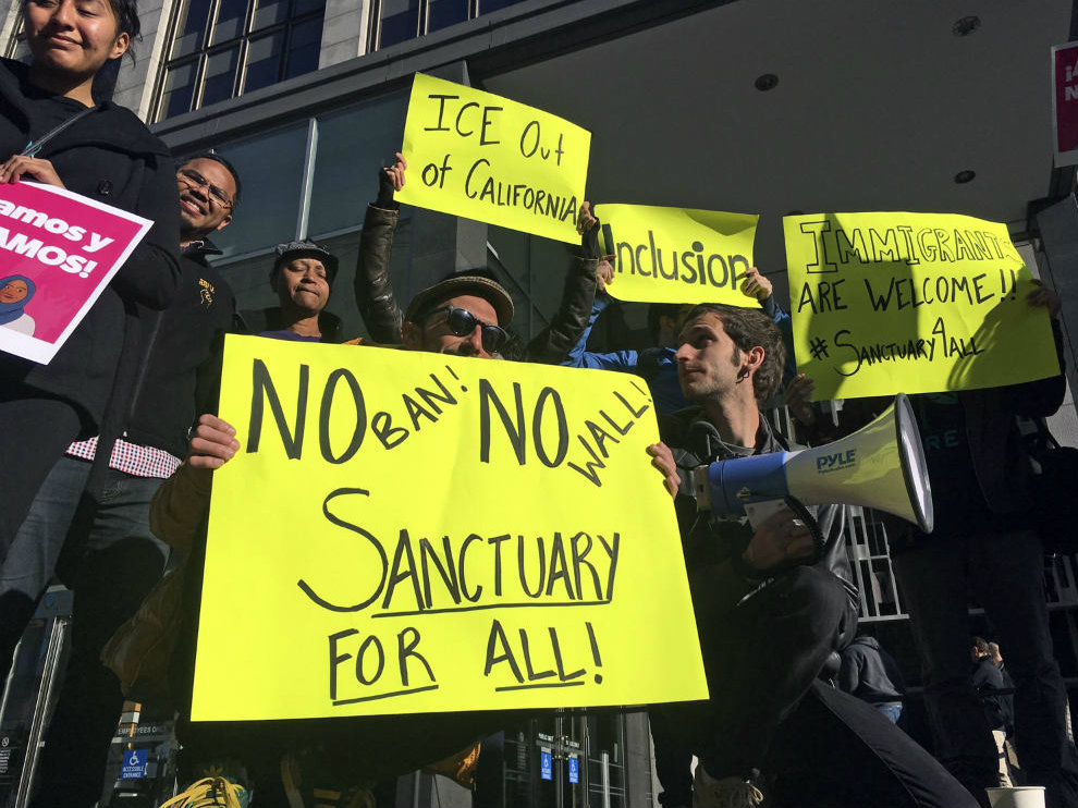 In this April 14, 2017 photo, protesters hold signs outside a courthouse where a federal judge was to hear arguments in the first lawsuit challenging President Donald Trump's order to withhold funding over the state's sanctuary laws.

