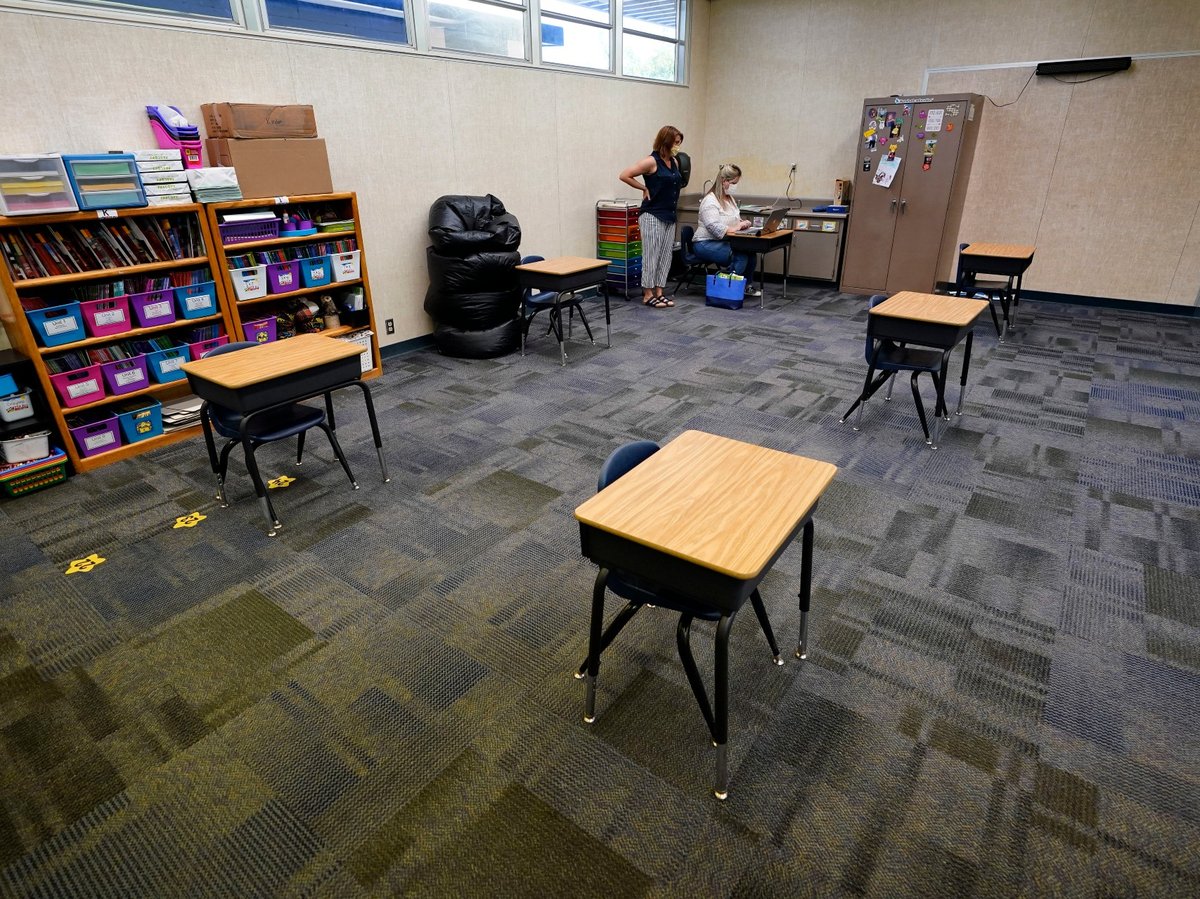 In this Aug. 19, 2020 file photo, teachers Andrea Gordon, left, and Melissa Stacy go over plans for the possibility of classroom learning, among socially-distanced desks at Palm Vista Elementary School in Twentynine Palms, Calif.