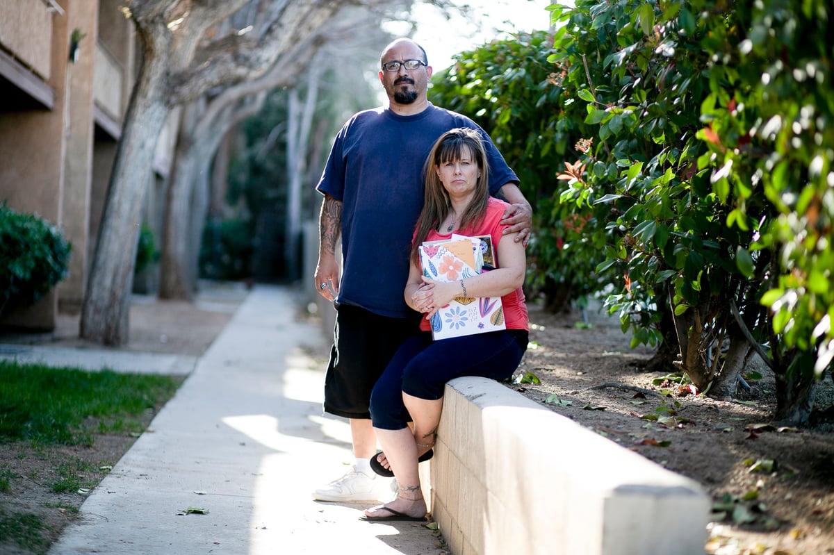 Stacy Lira and her husband of 28 years, Armando, outside their home in Victorville on March 29, 2021. She is holding a folder full of unemployment paperwork.