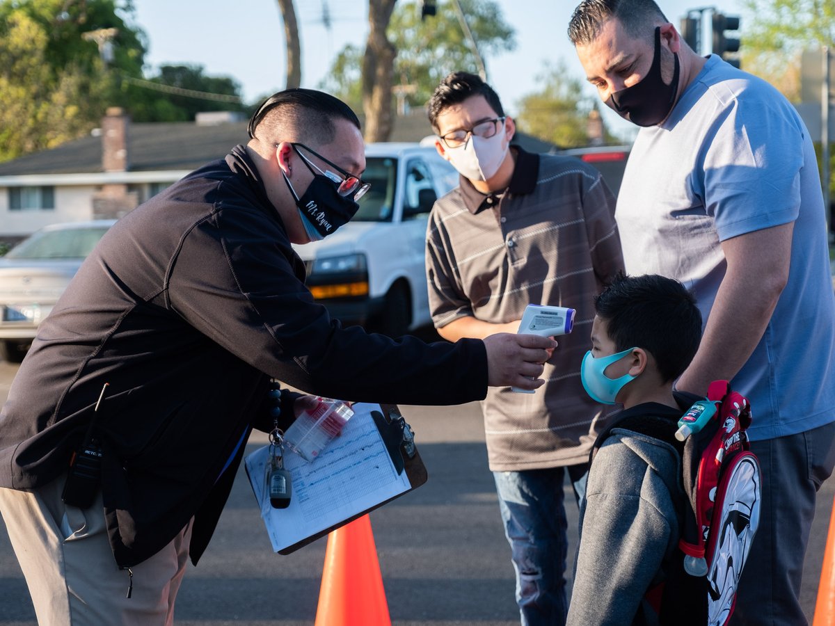 Program Manager Ryan Saechin checks Luke Henley's, 5, temperature before allowing him onto campus at John Cabrillo Elementary School, Thursday, April 8, 2021.