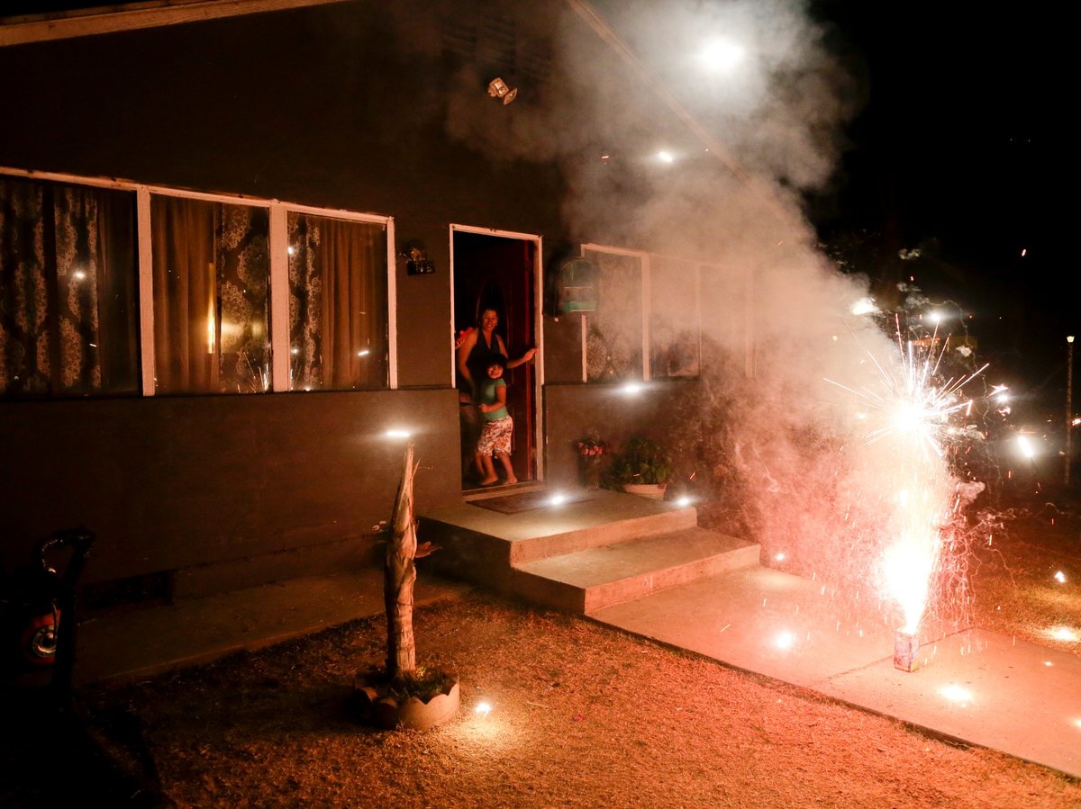 In this July 2, 2015 photo, Maria Marquez and her granddaughter Yaritza Pizano, 4, run inside for cover as fireworks burst in front of their home in the community of Okieville, on the outskirts of Tulare, Calif.
