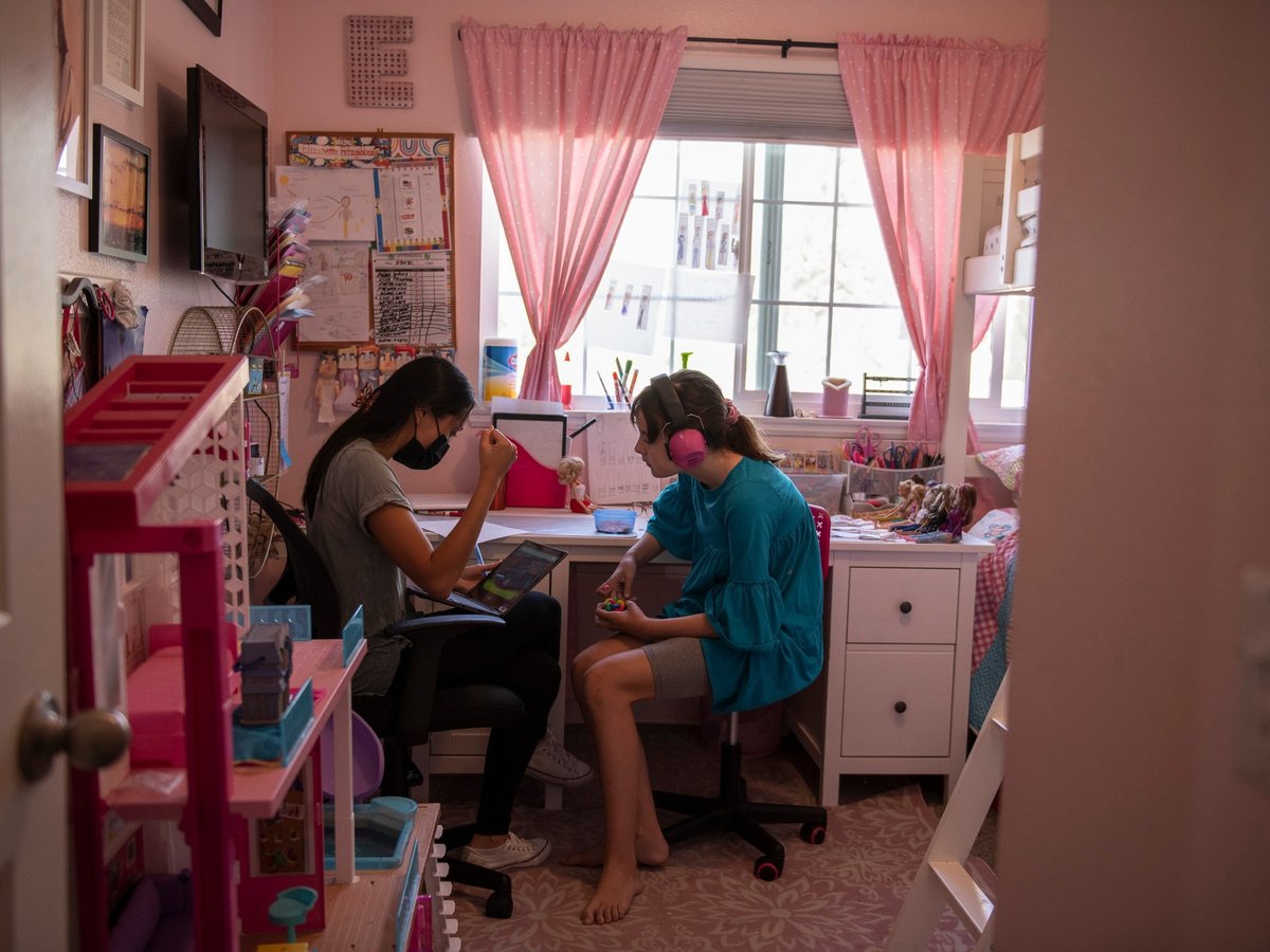 Ellie sits in her room with a behavioral therapist during class time in Monrovia, on Sept. 15, 2021. "There is no way to go back with 37 kids in a classroom," Julie Fitzgibbons, the mother of triplets, said.