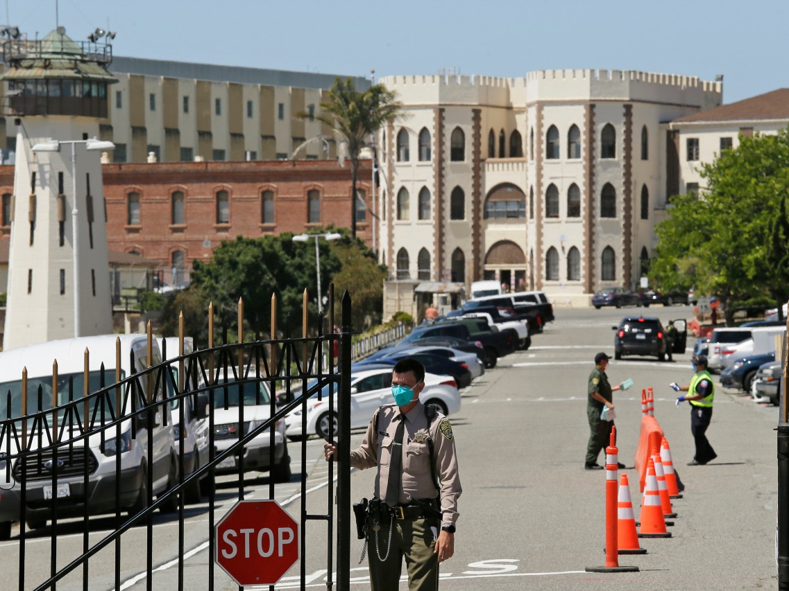In this July 9, 2020, file photo, a correctional officer closes the main gate at San Quentin State Prison in San Quentin, Calif.