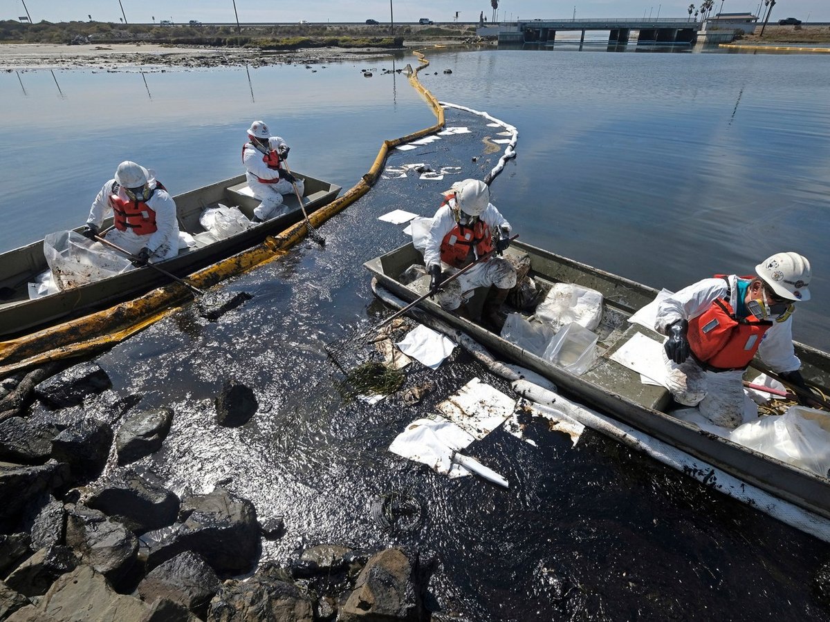 Cleanup contractors deploy skimmers and floating barriers known as booms to try to stop more oil from seeping into the Talbert Marsh in Huntington Beach on Oct. 3, 2021.