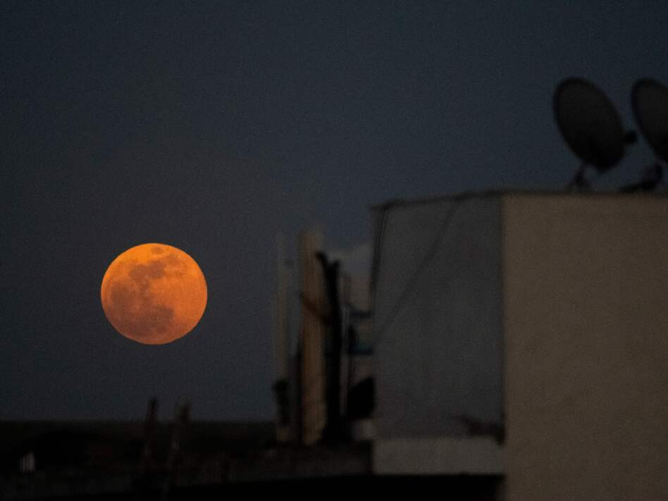The super blood noon rises over a residential area in New Delhi during a total lunar eclipse in May.