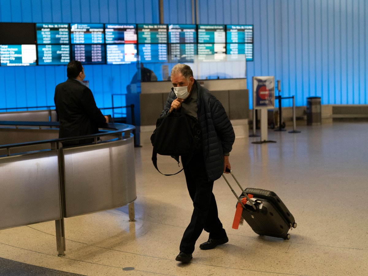 A traveler adjusts his face mask as he walks through the arrivals area at the Los Angeles International Airport in Los Angeles, Nov. 30, 2021.