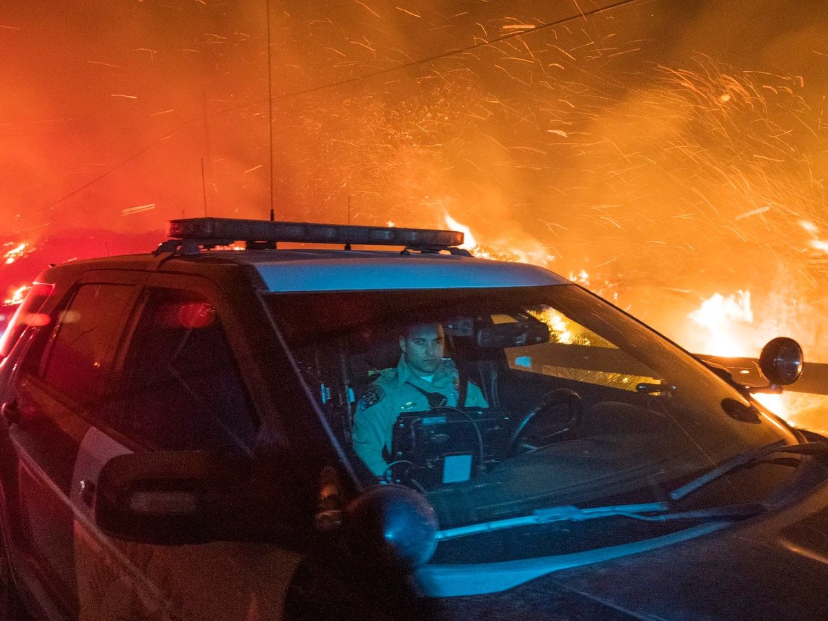 A California Highway Patrol officer drives south on Highway 1 as the Colorado Fire burns near Big Sur, Calif., on Friday.
