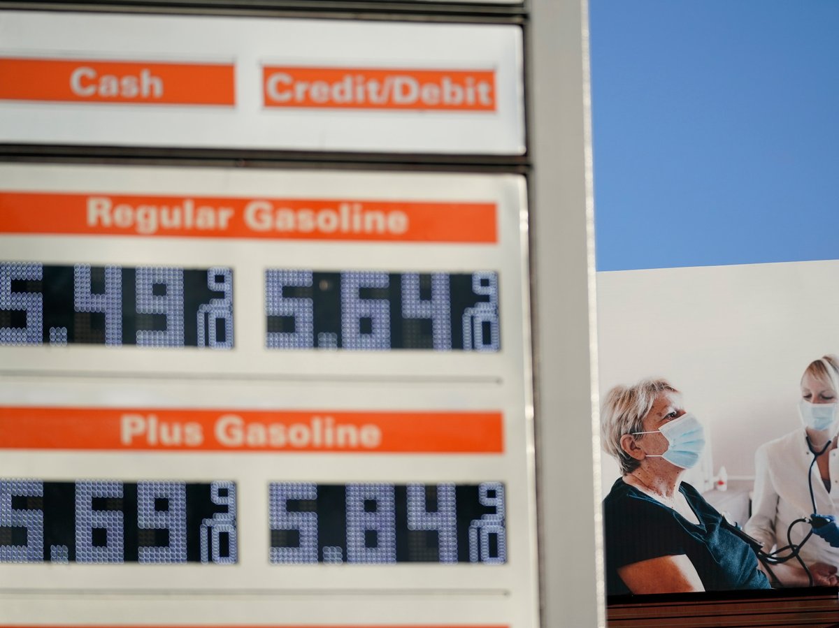 A billboard showing a woman getting her blood pressure taken stands behind a sign displaying gas prices in downtown Los Angeles, Wednesday, March 9, 2022.