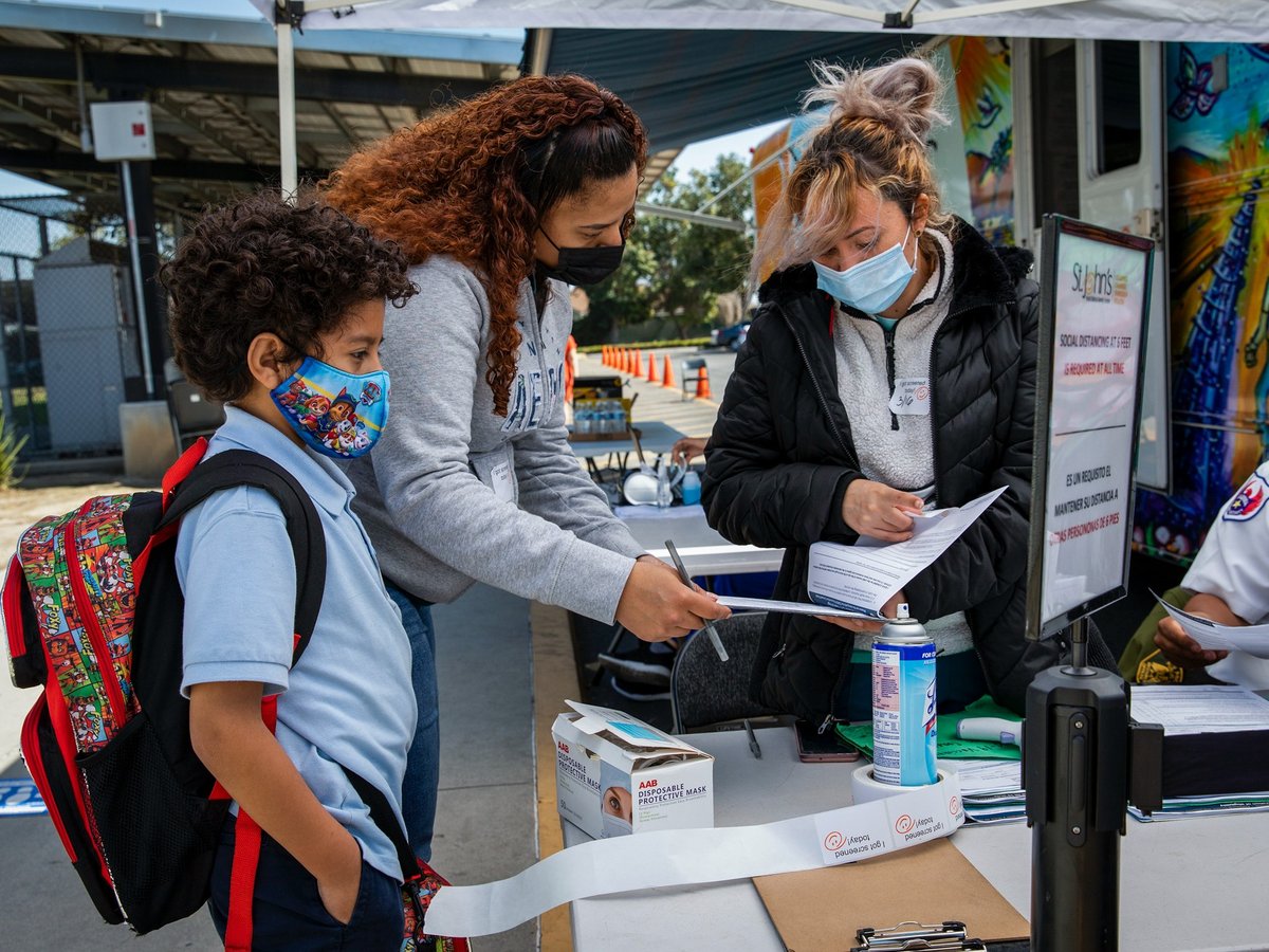 Jayden Elizondo, 5, waits with his mother, Jennifer Paices, as Maritza Thomas helps them fill out Covid-19 vaccination forms at a St. John’s Well Child and Family Center mobile health clinic at Helen Keller Elementary School in Los Angeles.