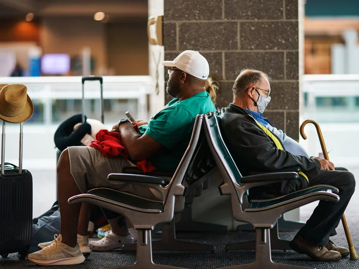 Travelers sit in a waiting area at Rhode Island T.F. Green International Airport in Providence, R.I., Tuesday, April 19, 2022. A federal judge's decision to strike down the federal mask mandate has left travelers to assess the risks of public transit