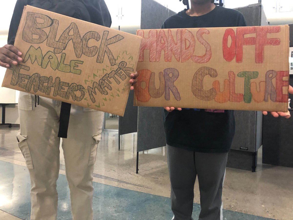 Two students hold posters expressing support for Jordan McGowan, the basketball coach and history/social science department chair at Rio Tierra Jr. High., and his importance to Black students.