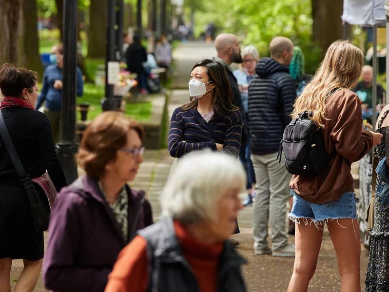 Shoppers walk through a Portland, Ore., farmers market in May. With the BA.5 variant driving case counts, public health experts are encouraging people to take precautions.