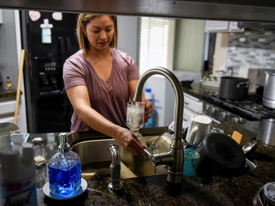 Esperanza Guerrero fills a glass with water in Teviston, on Oct. 20, 2021. California has begun the process of requiring water agencies to test their supplies for microplastics.