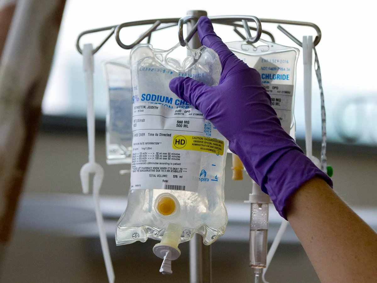 A nurse places a patient's chemotherapy medication on an intravenous stand.