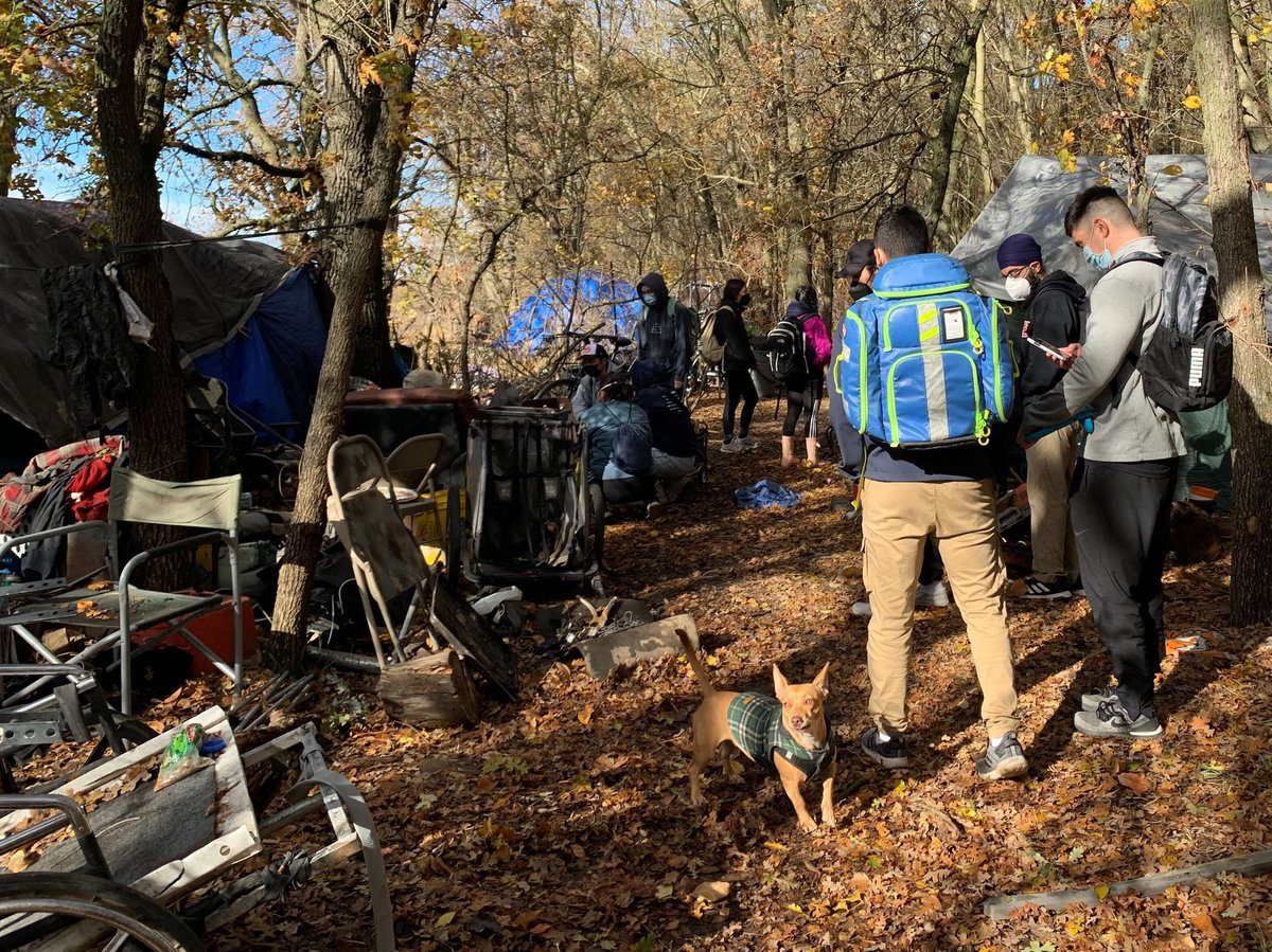 Volunteers with the Sacramento Street Medicine team gather in an encampment along the American River on Dec. 11, 2022.