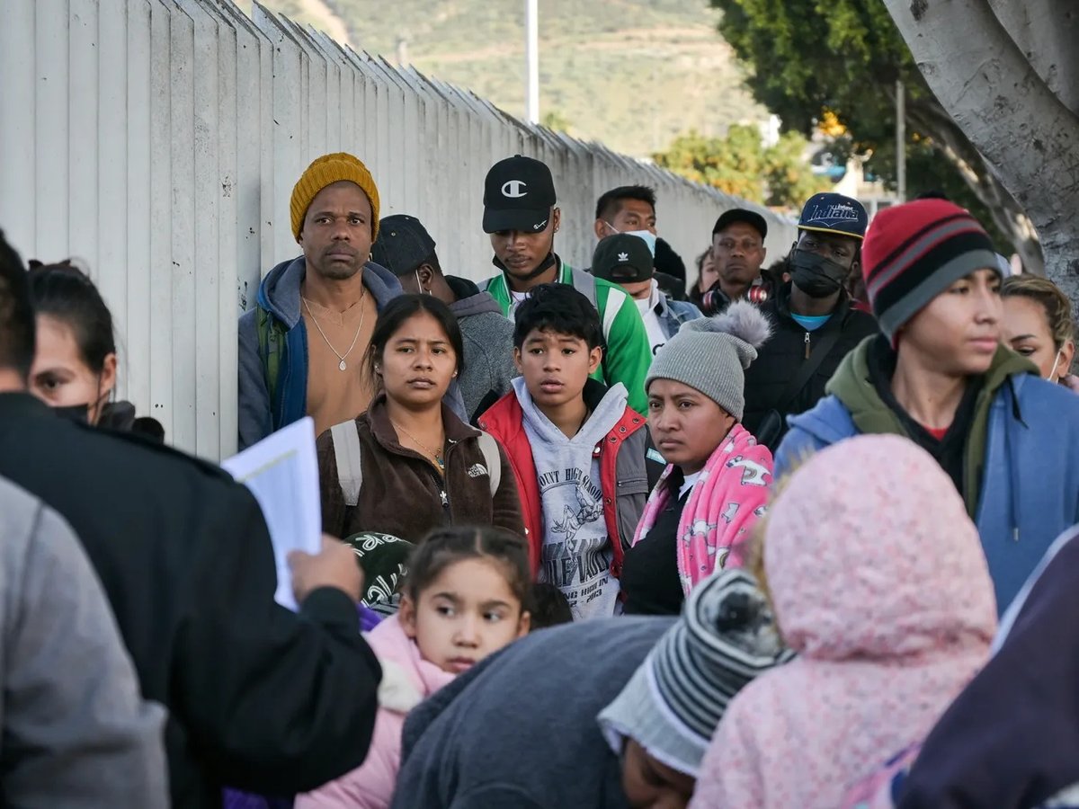 Migrants wait in line while California border activists organize the group to enter the U.S. and seek asylum through the Chaparral entryway in Tijuana, Mexico Dec. 22, 2022.