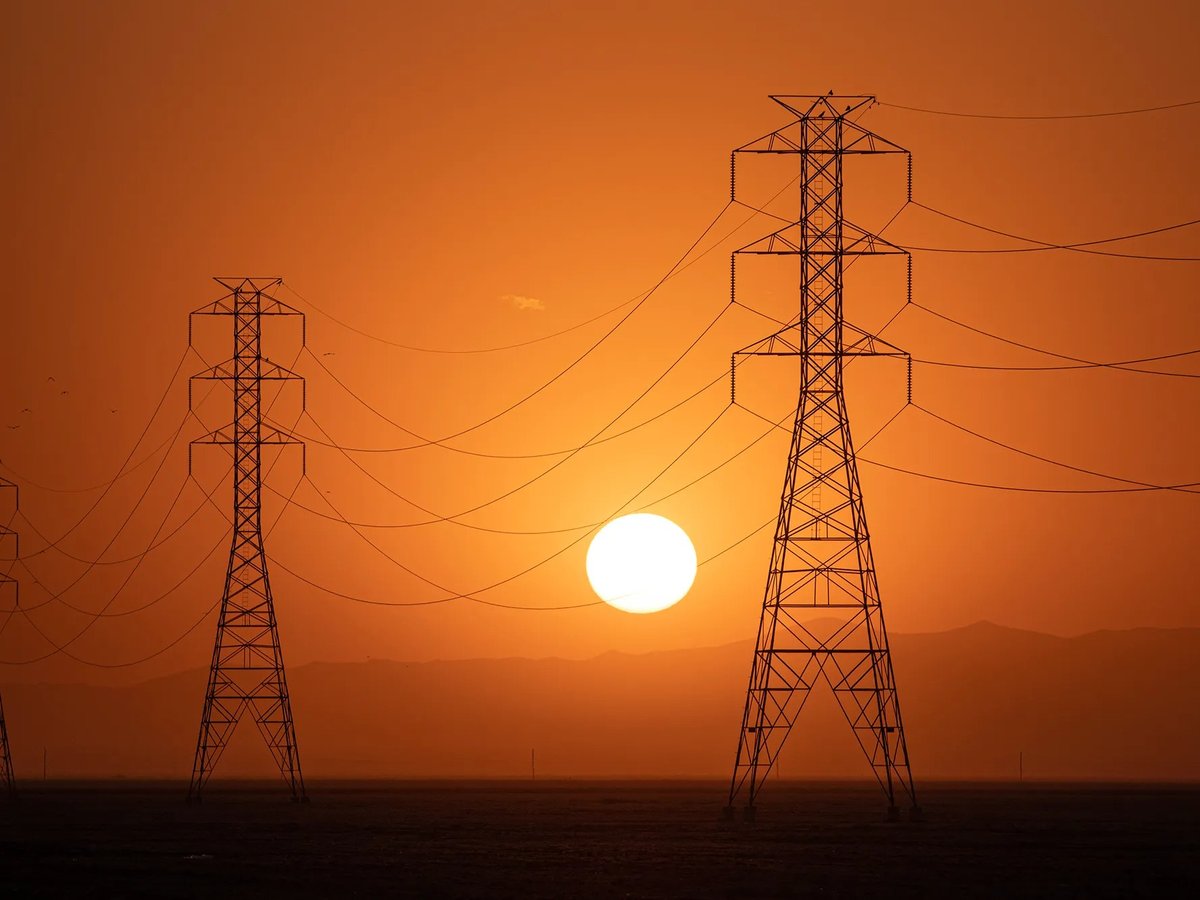 The sun sets behind a row of electric towers in Fresno County on Sept. 6, 2022.