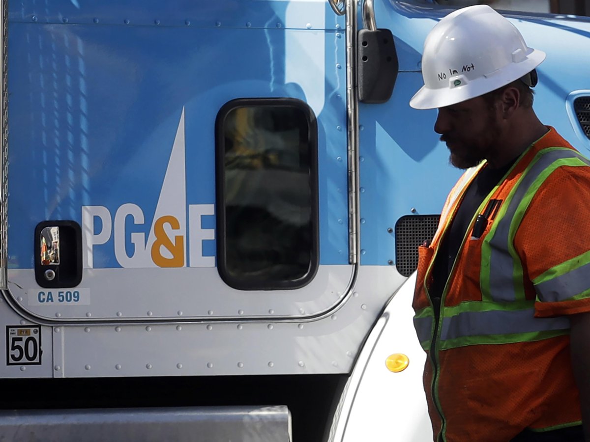 In this Aug. 15, 2019, file photo, a Pacific Gas & Electric worker walks in front of a truck in San Francisco.