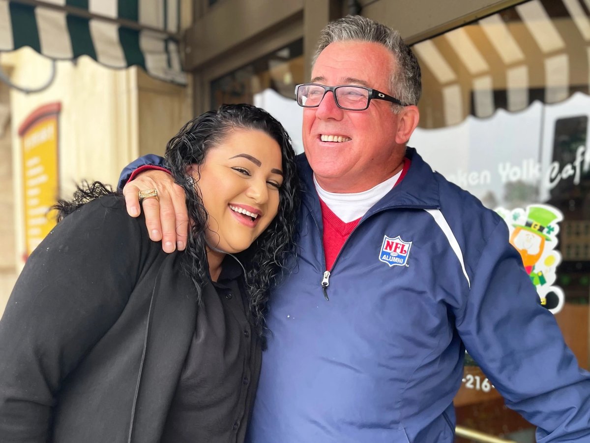 Craig McEwen, a former professional football player, hugs Veronica Ortiz, a lead care manager for Serene Health in San Diego County.