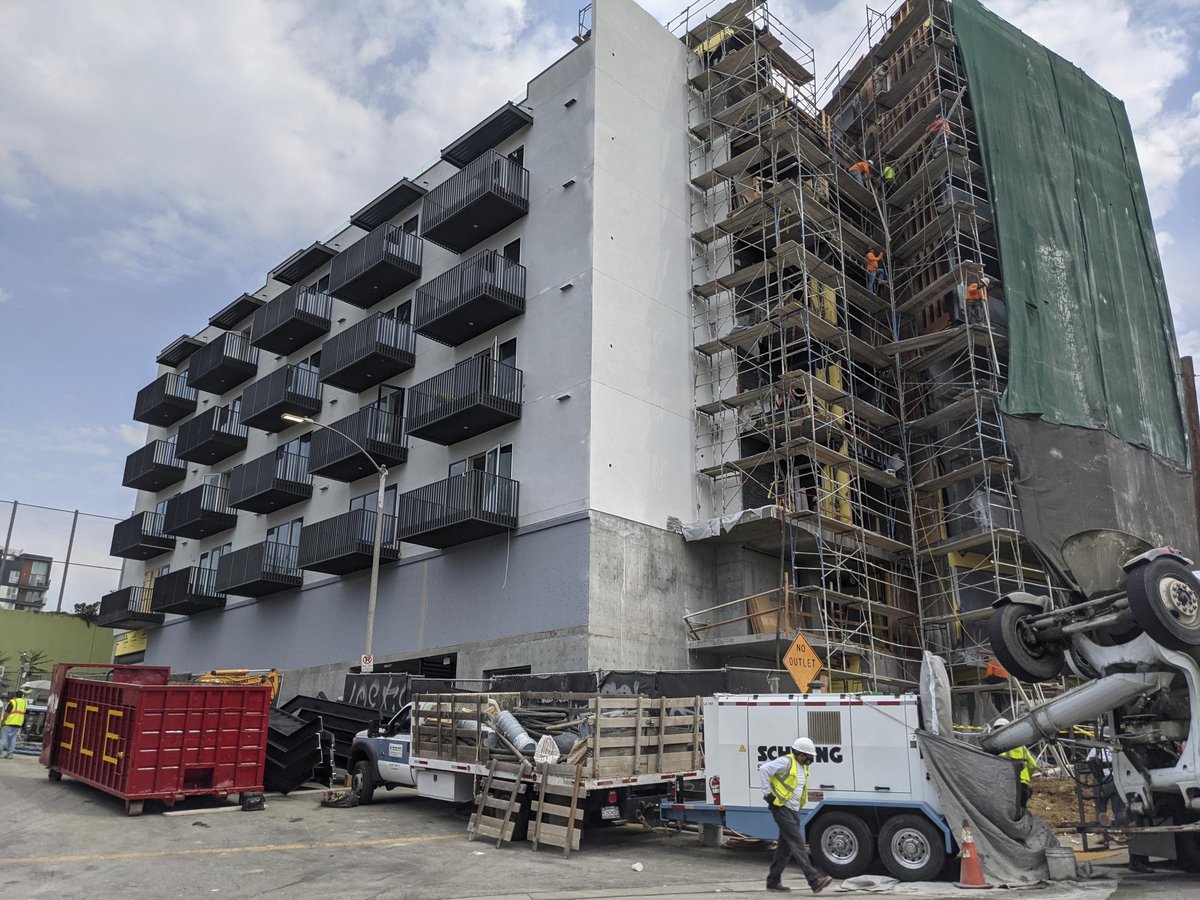 In this June 18, 2021, photo, construction workers finish the exterior of an apartment building downtown Los Angeles.