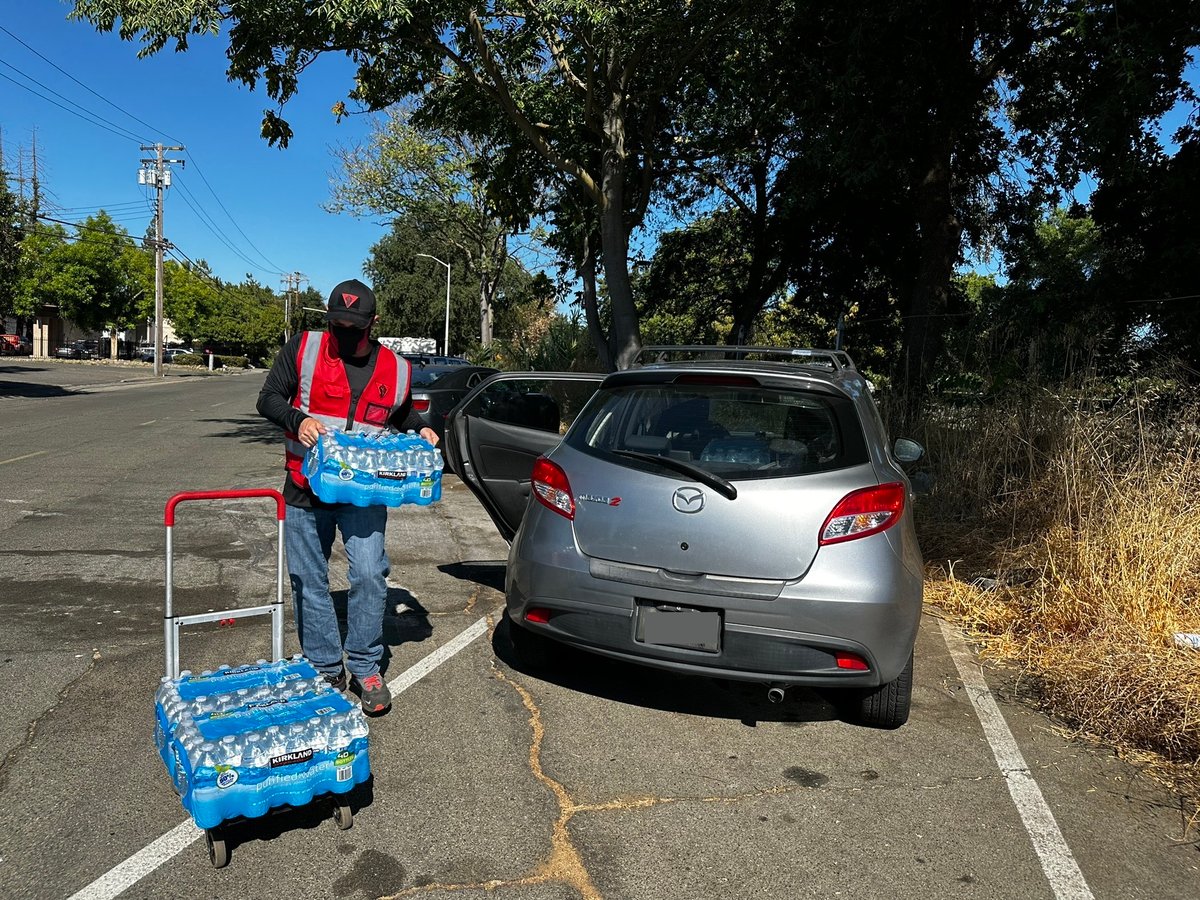 Crimson Fist, a director of Bay Area Super Heroes, unloads water bottles from their car to distribute at an encampment in Sacramento. July 14, 2023.