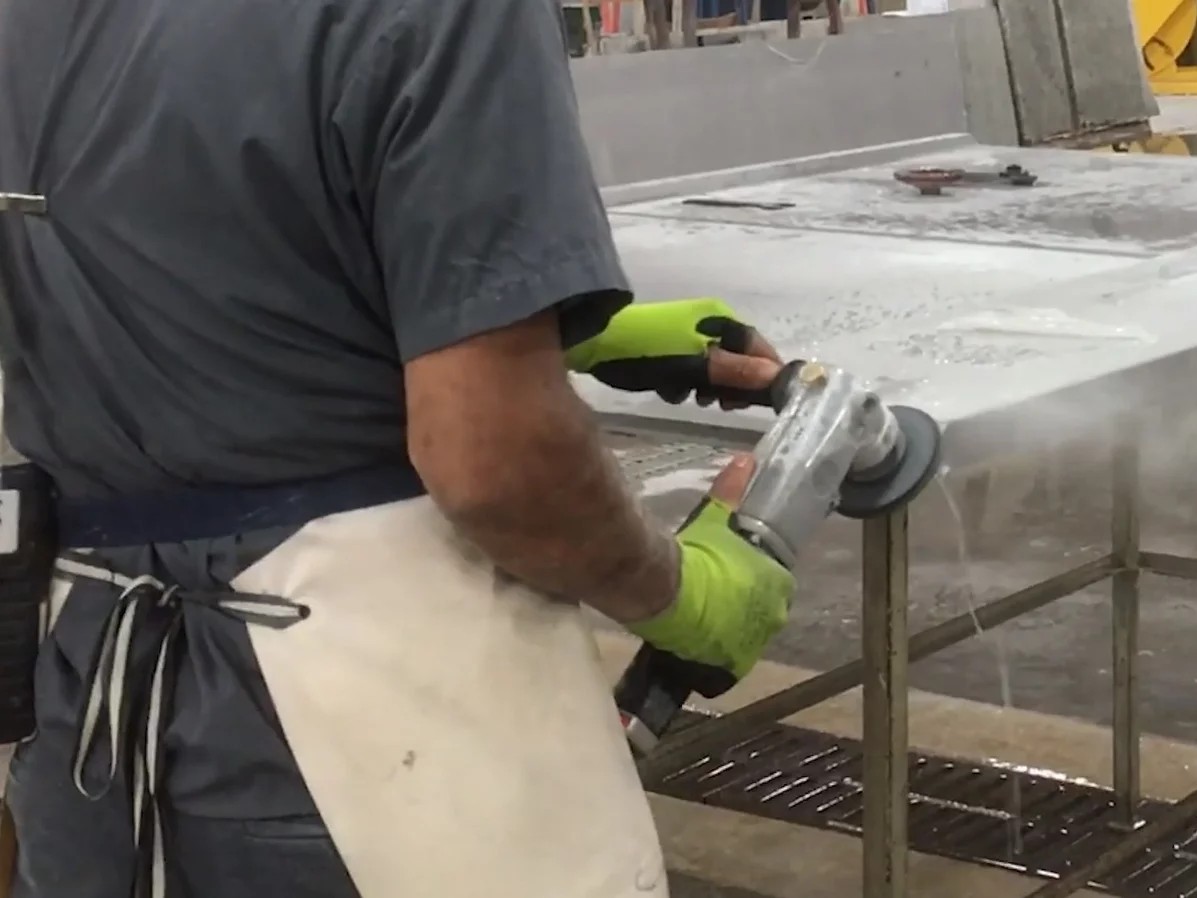 This image, from a video produced by government safety researchers, shows a countertop worker using a machine with a spray of water that's intended to control dust.