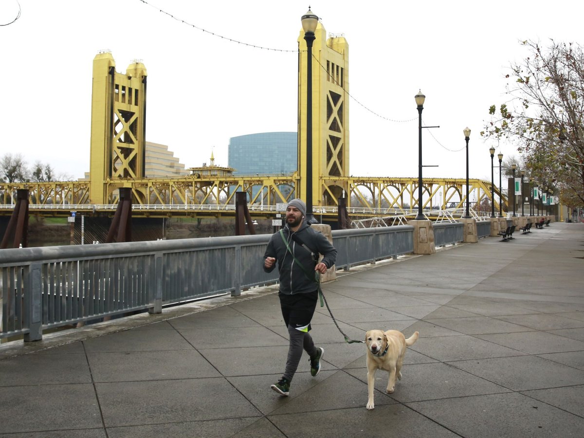 In this Jan. 9, 2018 photo, a man runs with his dog on the river walk along the Sacramento River.