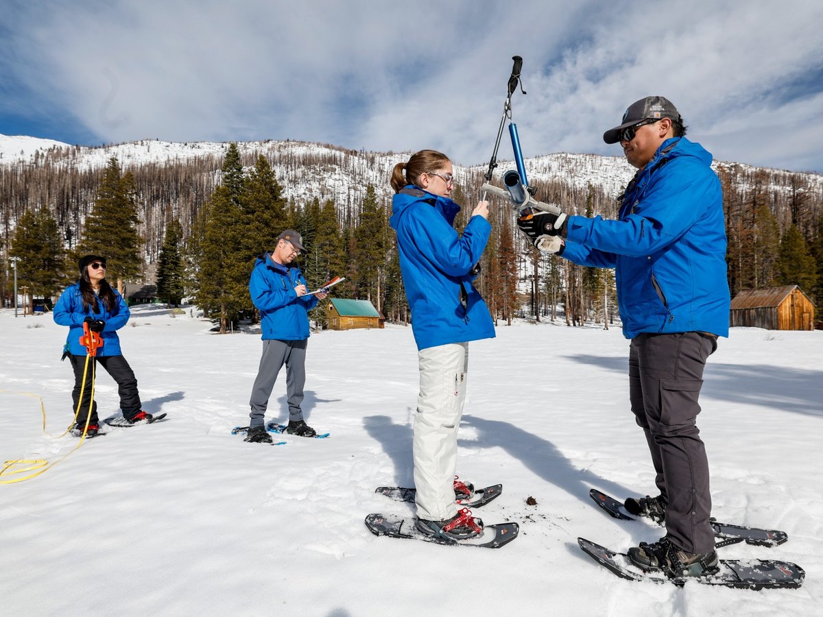 Sean de Guzman and Jordan Thoennes with the California Department of Water Resources weigh the aluminum snow depth survey pole during the second media snow survey of the season at Phillips Snow Station on Jan. 30, 2024.