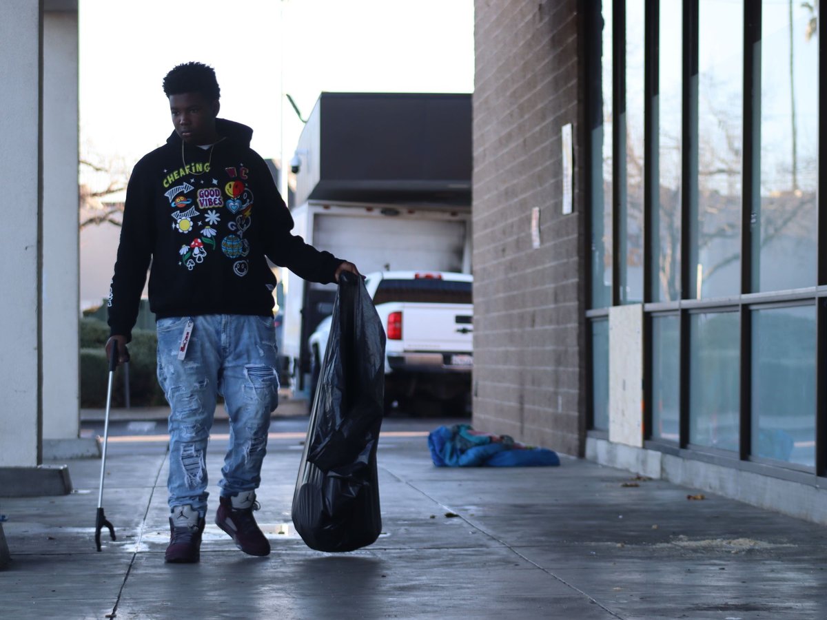 De'Andre Allen picks up bits of trash with handheld pincers as part of the Florin Road Beautification Project's litter clean-up efforts on Thursday, Jan. 25, 2024.