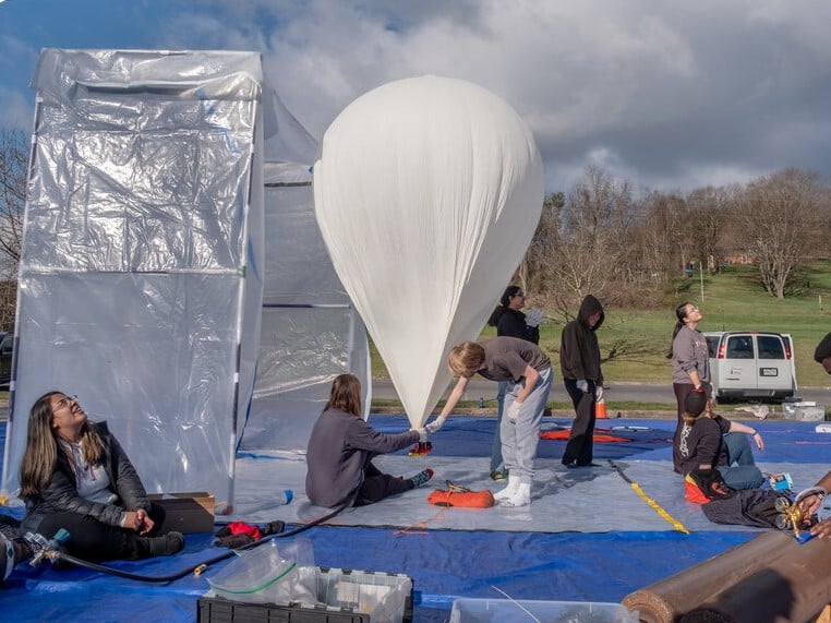 Student volunteers prepare a balloon for a morning launch in Cumberland, Md. On April 8, eclipse day, hundreds of balloons will be launched into the path of the eclipse to study the atmosphere.