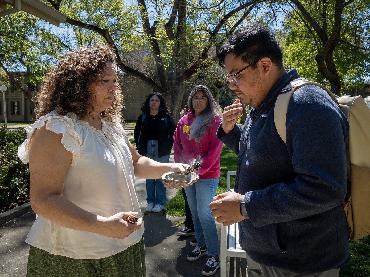 Carlos Morales and Michelle Villegas-Frazier participate in a sage burning ritual outside of the Native American Academic Student Success Center at UC Davis on April 1, 2024.