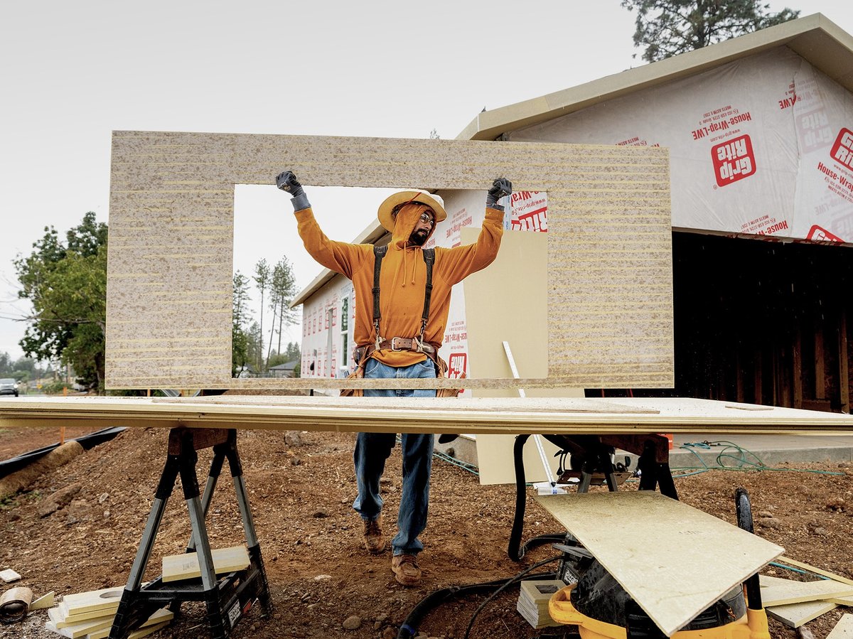 Jose Villanueva carries siding while building a home in Paradise on Oct. 25, 2023. The project is partly funded by ReCoverCA, a state program providing money to rebuild homes in disaster areas.