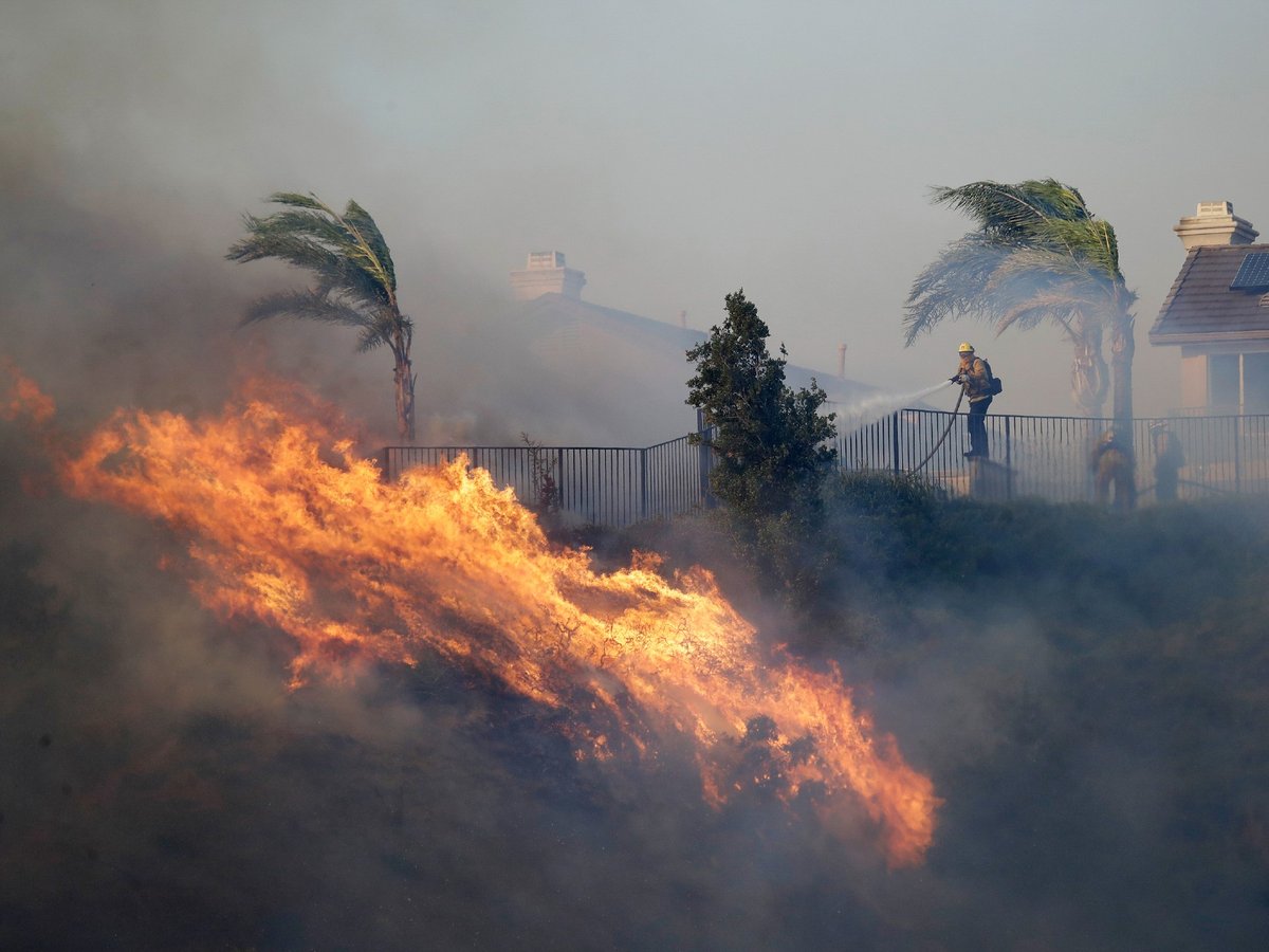 A firefighter sprays water in front of an advancing wildfire Friday, Oct. 11, 2019, in Porter Ranch, Calif.