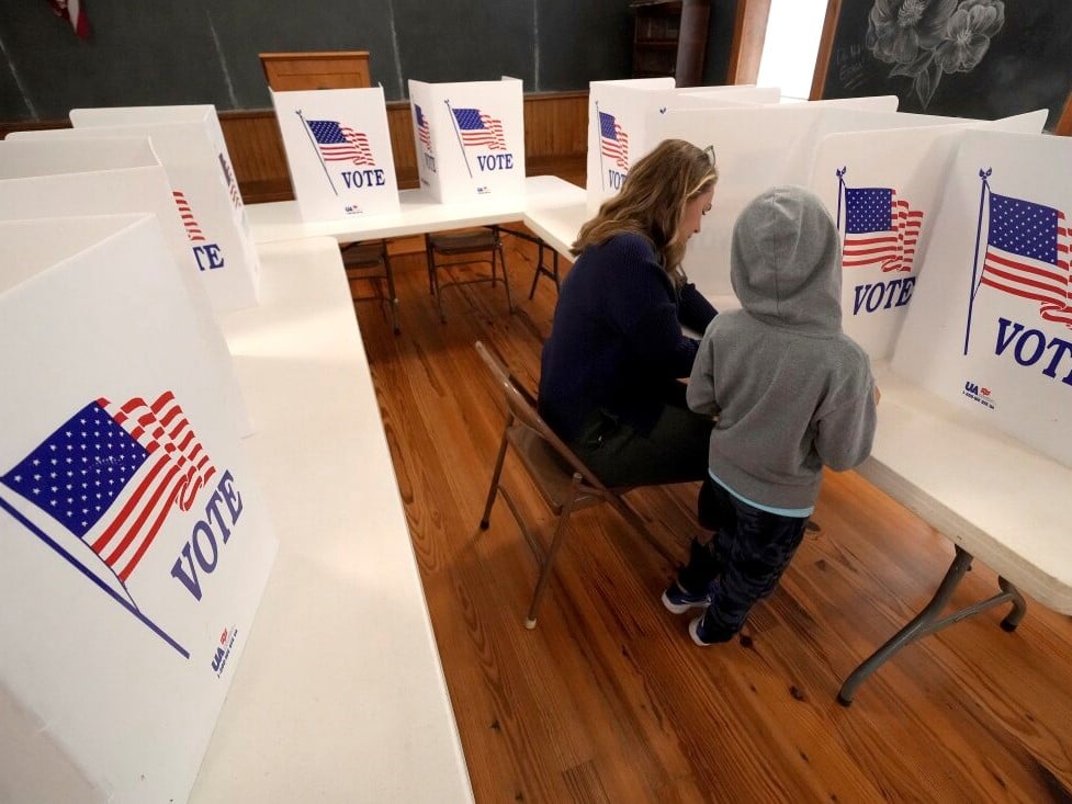 Aliza Bidinger is accompanied by her son Jayce, age 6, as she votes at the 146-year-old Buck Creek school on Election Day, Tuesday, Nov. 5, 2024, in rural Perry, Kan.