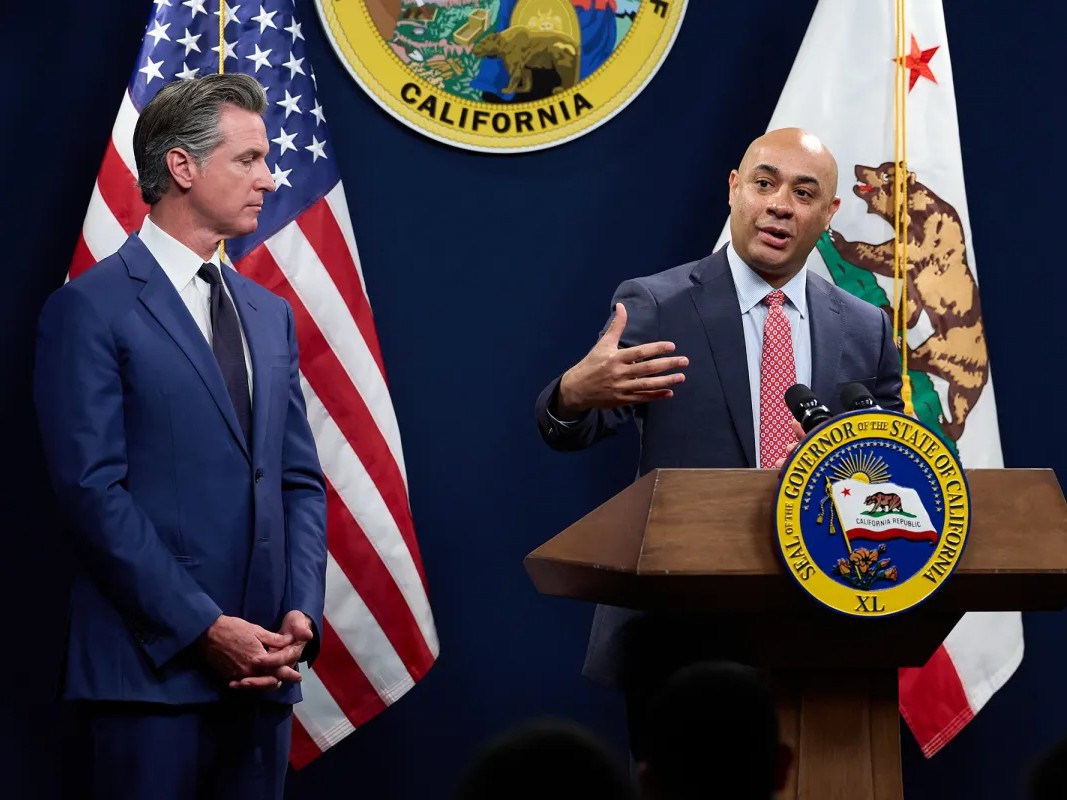Gov. Gavin Newsom, left, listens as Joe Stephenshaw, director of the Department of Finance, speaks during a press conference unveiling Newsom's revised 2024-25 budget proposal at the Capitol Annex Swing Space in Sacramento on May 10, 2024.