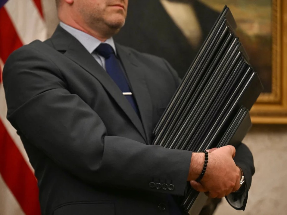 An aide holds executive orders to be signed by President Trump at the White House on Monday.