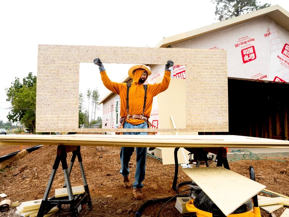 Jose Villanueva carries siding while building a home, Wednesday, Oct. 25, 2023, in Paradise, Calif. Most of the town burned in late 2018.