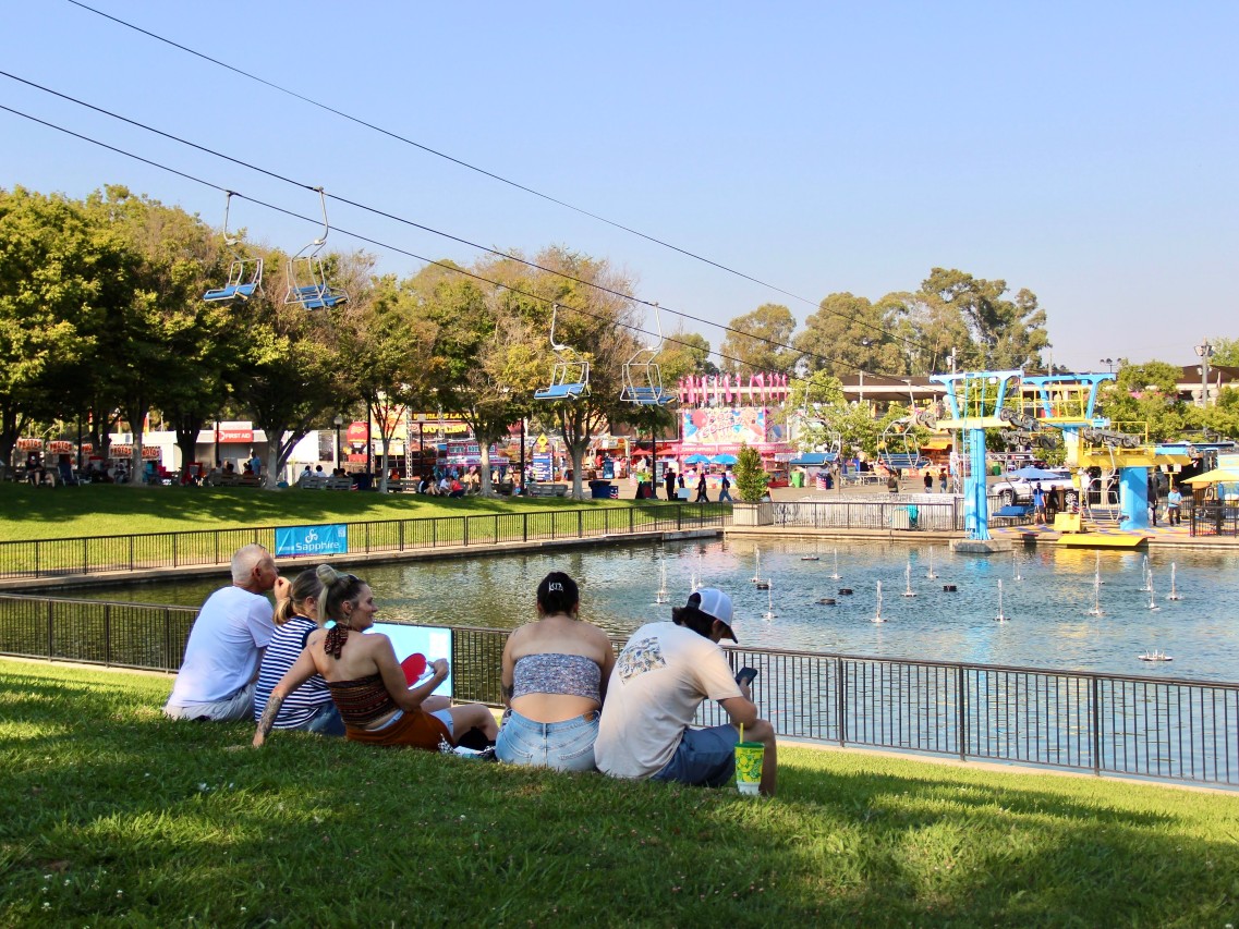Fairgoers take a break from festivities on the grass steps of the Fountains at Palm Ave during opening weekend of the California State Fair on Friday, July 11 at Cal-Expo in Sacramento.