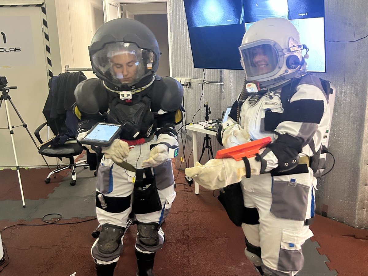 Two crew members in their EVA (extra vehicular activity or moonwalk) suits, which were worn to simulate walking on the surface of the moon. This donning process took about two hours.