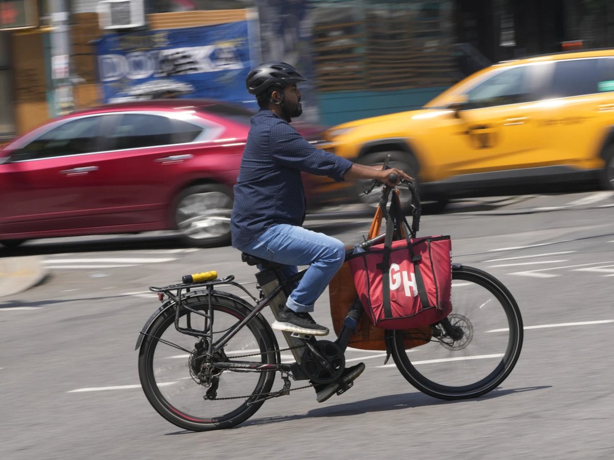 A delivery worker rides a motorized bicycle in New York, Tuesday, July 25, 2023.