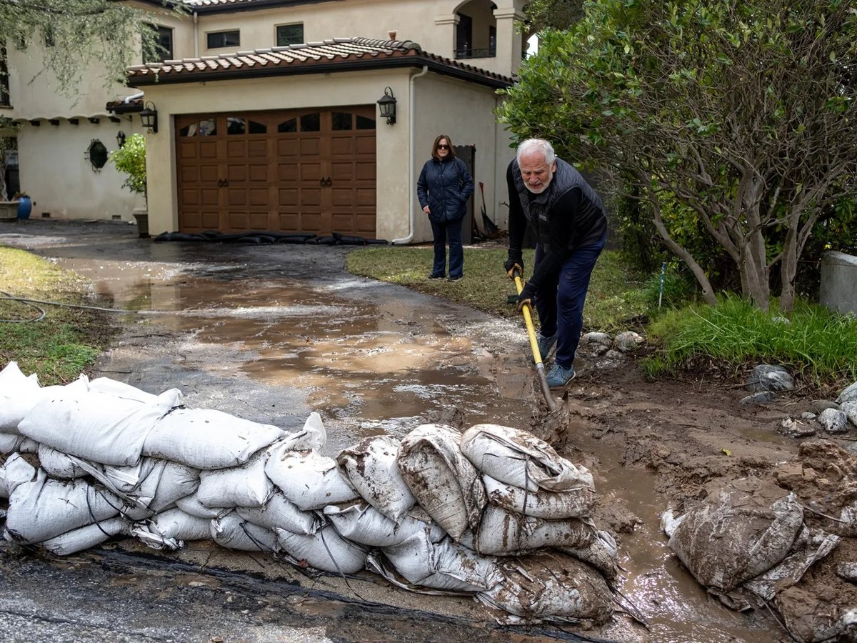 Ray Farhang clears out mud from his driveway after heavy rainfall triggered multiple mudslides in the Eaton Fire burn scar area in Altadena on Feb. 14, 2025.