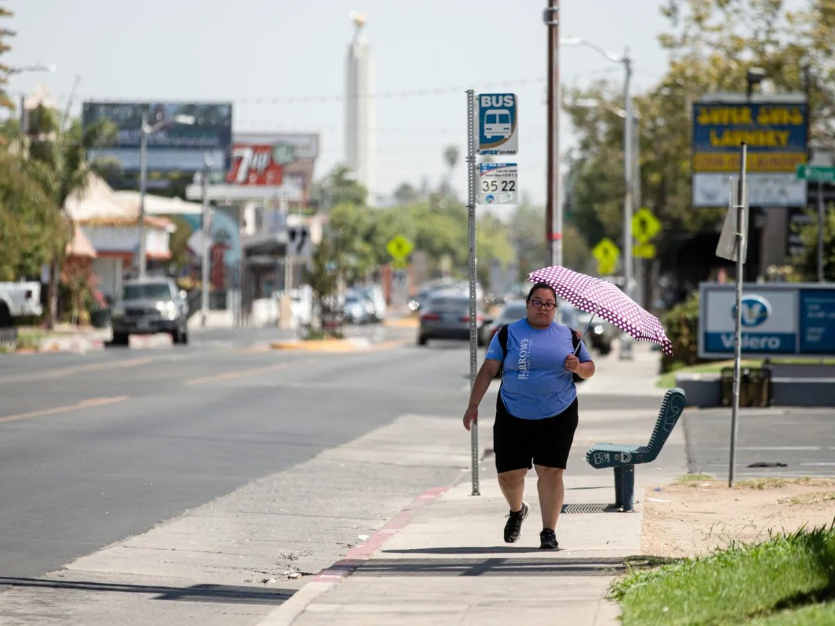 A Fresno resident uses an umbrella to shield herself from the sun on Aug. 30, 2022, as a heat wave descended over California.