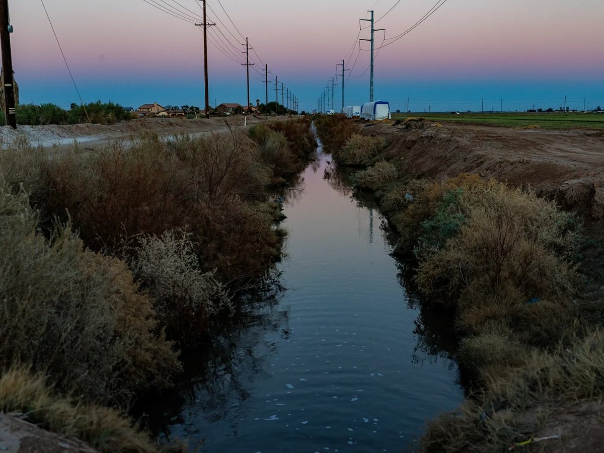 An irrigation ditch runs between farm land, on the right, and a proposed 950,000-square-foot data center, on the left, in Imperial County on March 11, 2026.