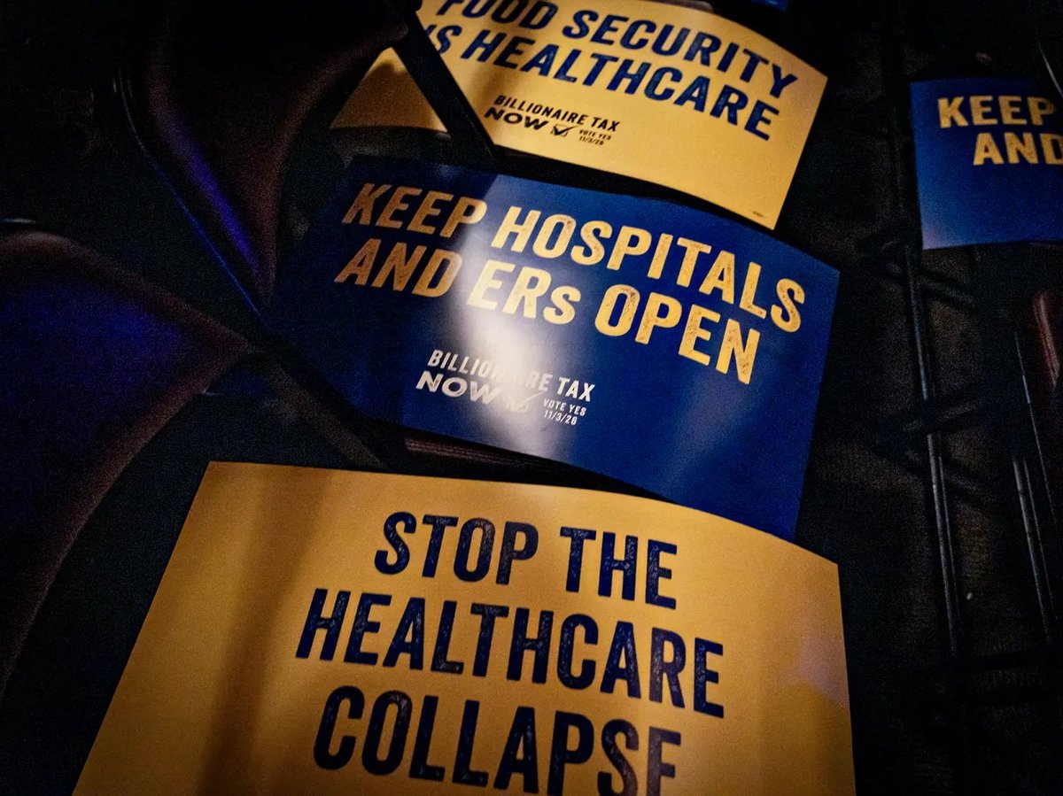 Signs reading “A Billionaire Tax Now” rest on chairs at a Billionaire Tax Now rally where Sen. Bernie Sanders is set to speak in Los Angeles on Feb. 18, 2026.