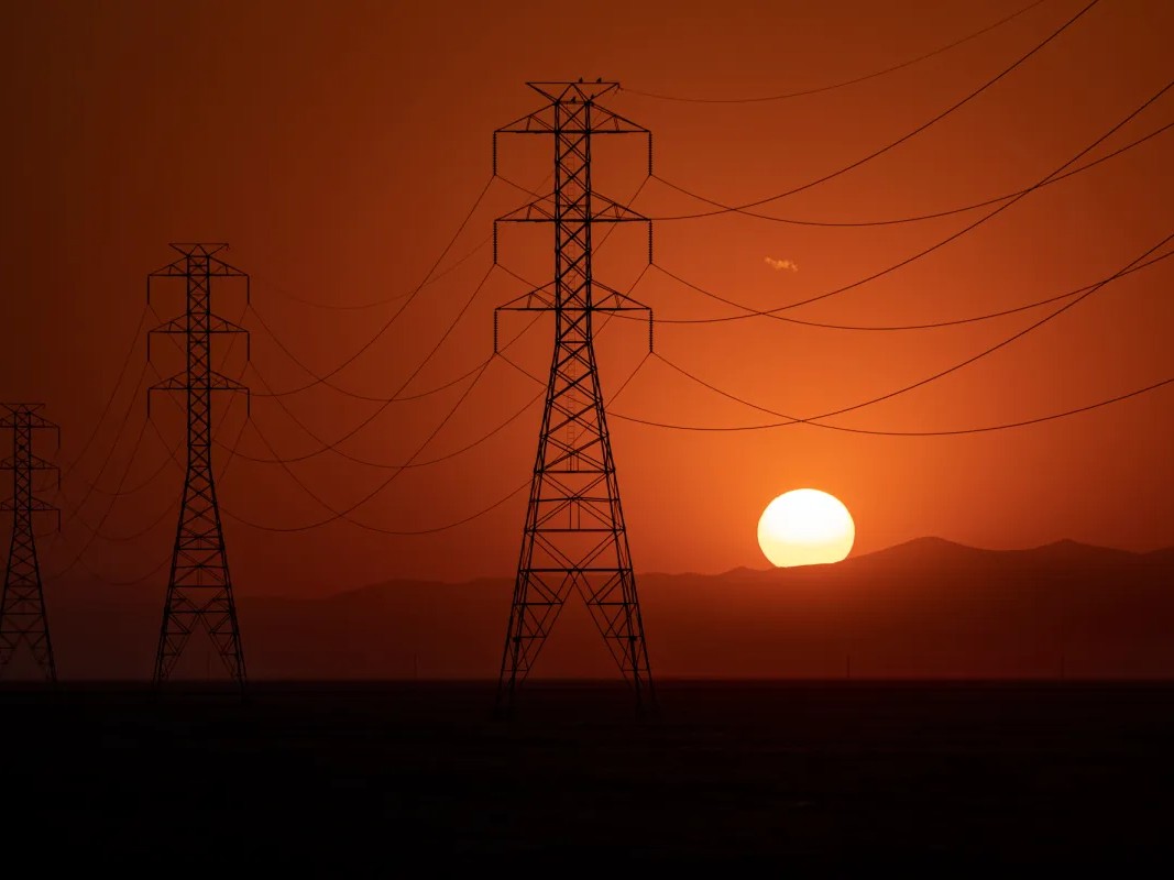 The sun sets behind a row of transmission towers as temperatures rise to a scorching 114 degrees in Fresno County on Sept. 6, 2022.