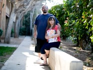 Stacy Lira and her husband of 28 years, Armando, outside their home in Victorville on March 29, 2021. She is holding a folder full of unemployment paperwork.