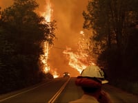 A car passes through flames on Highway 299 as the Carr Fire burns through Shasta, Calif., on Thursday, July 26, 2018.