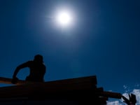 Two construction workers load timbers onto the roof of a minivan in Los Angeles, Thursday, Sept. 1, 2022. California is in a state of emergency as a brutal heat wave brings the threat of power outages and wildfires.