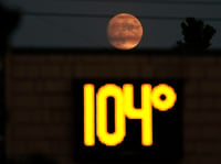 A temperature of 104 degrees is displayed on a digital thermometer as the moon rises over Sacramento, Calif., Thursday, Sept. 8, 2022. A heat wave setting several high temperature marks in California.