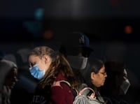 Travelers with protective face masks wait in line to check in at the Los Angeles International Airport in Los Angeles, Monday, Dec. 19, 2022.